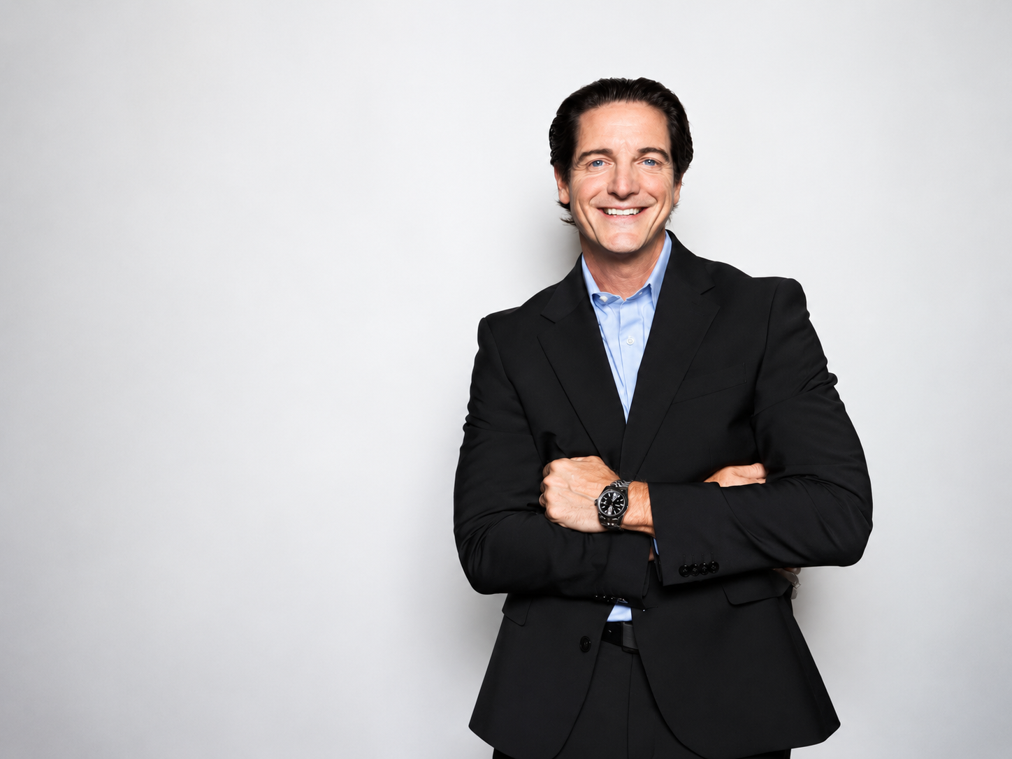 Rob Bilson in a black suit and light blue shirt, arms crossed